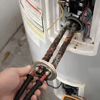 Licensed plumber servicing an electric water heater in a Nampa, Idaho home